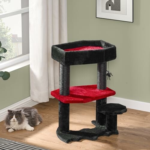 Cat resting beside a black and red cat tree in a room.